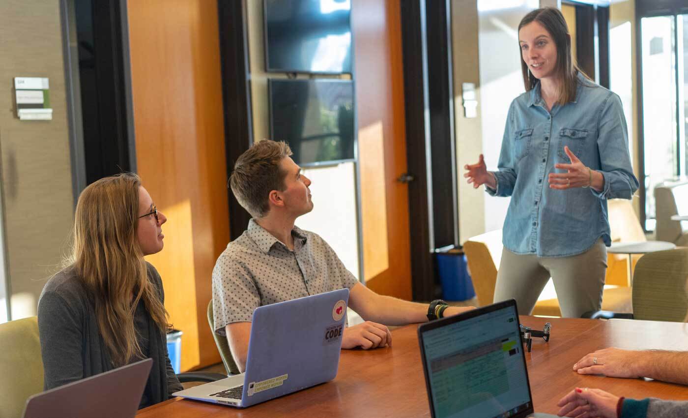 Shows three employees having a discussion - Cost of payroll guide